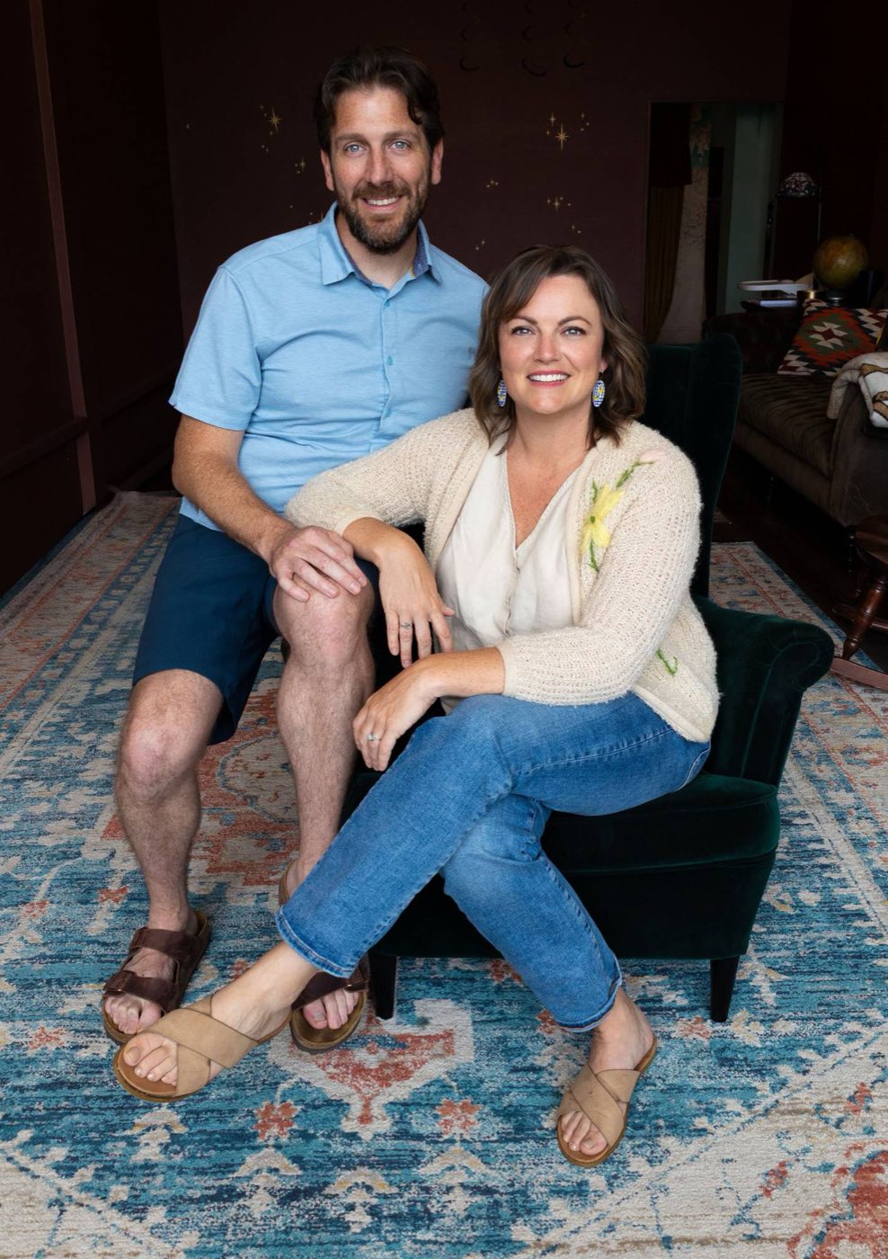 Emily Mitchell and Michael Plant, founders of The Wandering Lantern, sitting together on a green velvet armchair in the store